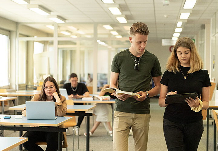 Etudiants qui discutent et qui lisent un livre et une tablette tactile