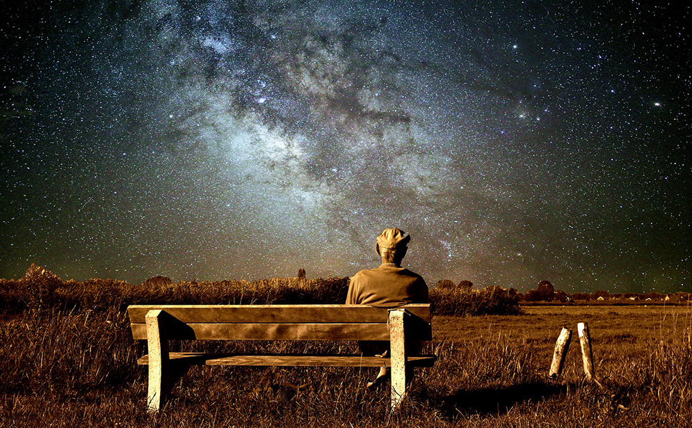 Personne âgée assis sur un banc et regardant les étoiles